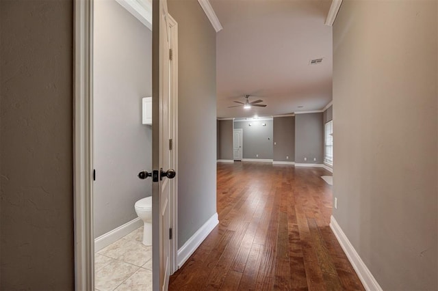 corridor featuring crown molding, baseboards, wood-type flooring, and visible vents