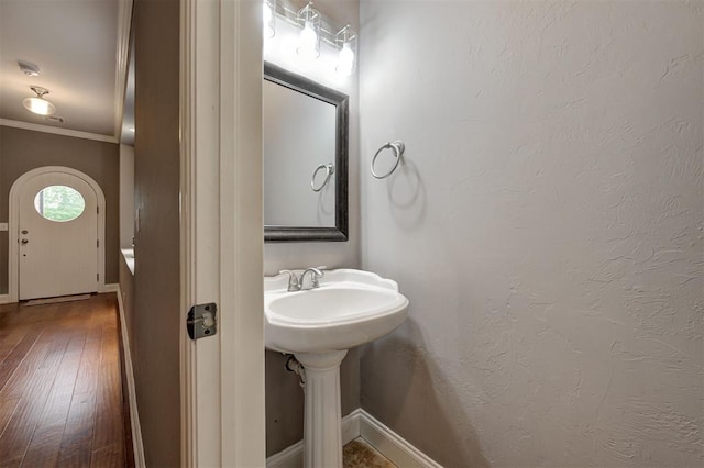 bathroom featuring baseboards, ornamental molding, and wood finished floors