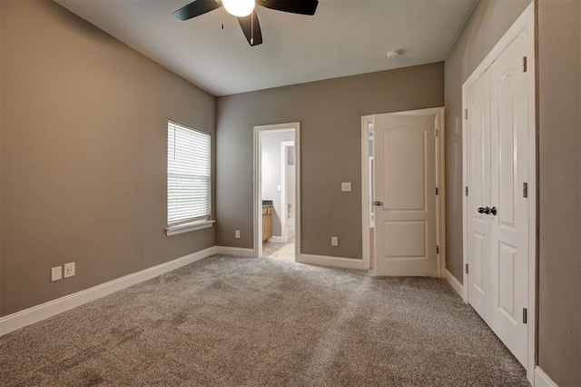 unfurnished bedroom featuring baseboards, light colored carpet, ceiling fan, and ensuite bath