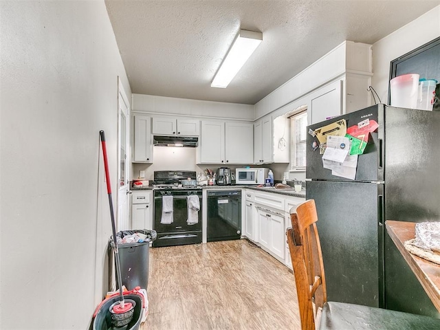 3205 S Madole Blvd, Oklahoma City, OK 73159 - kitchen with black appliances, under cabinet range hood, white cabinetry, light wood-type flooring, and a textured ceiling