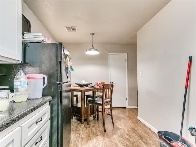 3205 S Madole Blvd, Oklahoma City, OK 73159 - kitchen featuring light wood finished floors, dark countertops, white cabinetry, baseboards, and decorative light fixtures
