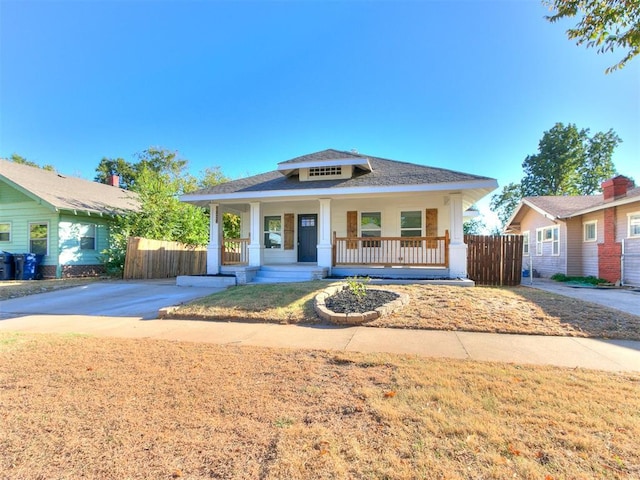 bungalow-style house featuring fence, covered porch, and roof with shingles