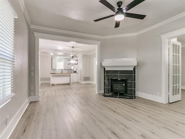unfurnished living room featuring ornamental molding, visible vents, light wood finished floors, and ceiling fan with notable chandelier