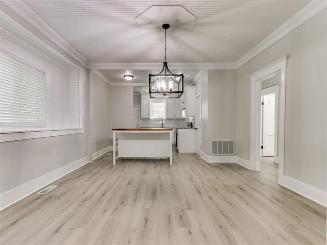 unfurnished dining area with ornamental molding, visible vents, light wood finished floors, and a chandelier