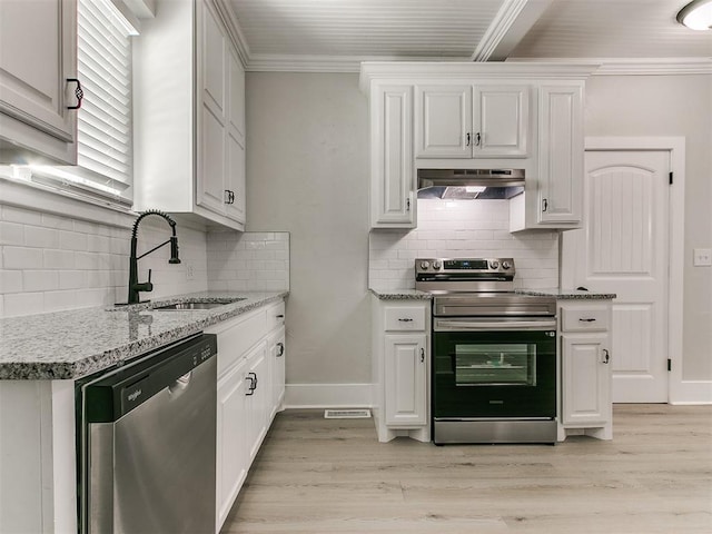 kitchen with a sink, under cabinet range hood, crown molding, stainless steel appliances, and backsplash