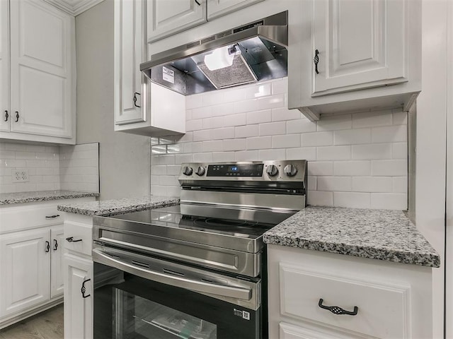 kitchen with white cabinets, under cabinet range hood, backsplash, and stainless steel electric stove