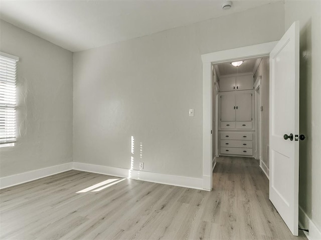 unfurnished bedroom with baseboards, light wood-type flooring, and attic access