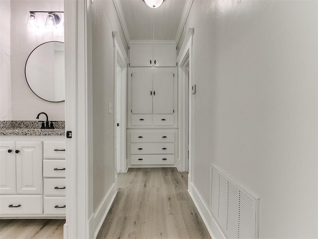 hall with ornamental molding, visible vents, attic access, and light wood-style floors