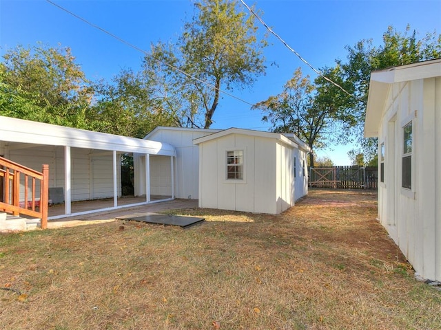 view of outdoor structure with a carport, an outbuilding, and fence