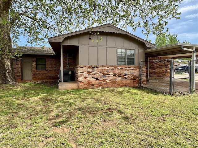 136 Skyline Dr, Chickasha, OK 73018 - view of front of home featuring board and batten siding, brick siding, a front yard, fence, and a gate