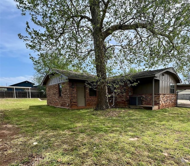 136 Skyline Dr, Chickasha, OK 73018 - rear view of property with board and batten siding, a yard, fence, brick siding, and central AC unit
