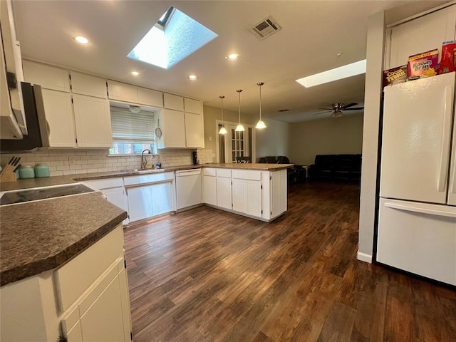 136 Skyline Dr, Chickasha, OK 73018 - kitchen featuring a sink, white appliances, a peninsula, a skylight, and decorative backsplash