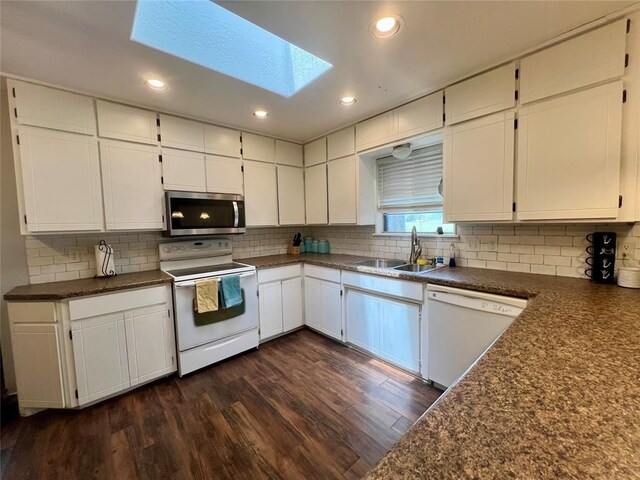 136 Skyline Dr, Chickasha, OK 73018 - kitchen featuring a sink, dark wood-style flooring, dark countertops, white appliances, and a skylight