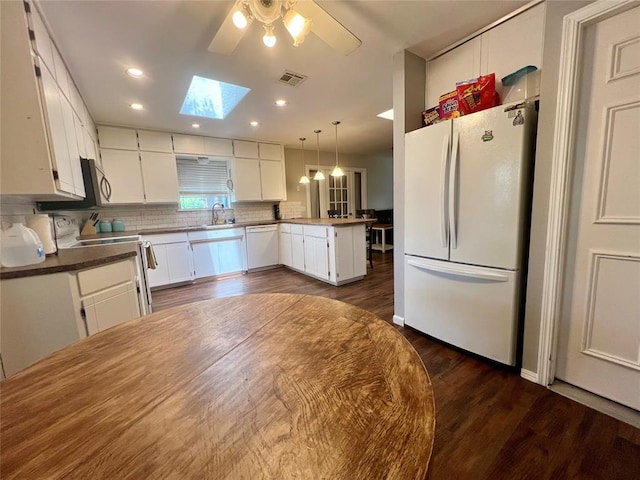 136 Skyline Dr, Chickasha, OK 73018 - kitchen with tasteful backsplash, white appliances, a peninsula, visible vents, and a skylight