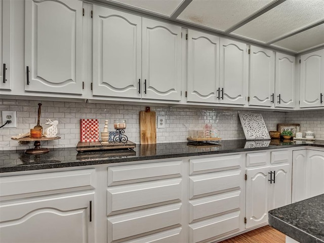 7 Kaross Dr, Shawnee, OK 74801 - kitchen featuring dark stone countertops, decorative backsplash, white cabinetry, and light wood-type flooring