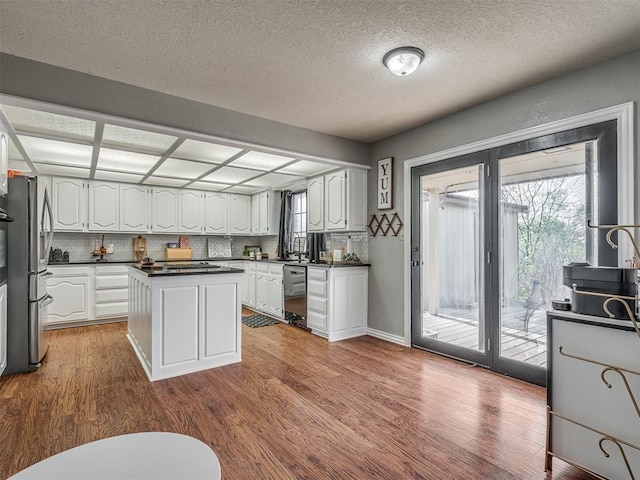 7 Kaross Dr, Shawnee, OK 74801 - kitchen with dark countertops, white cabinets, wood finished floors, appliances with stainless steel finishes, and a kitchen island