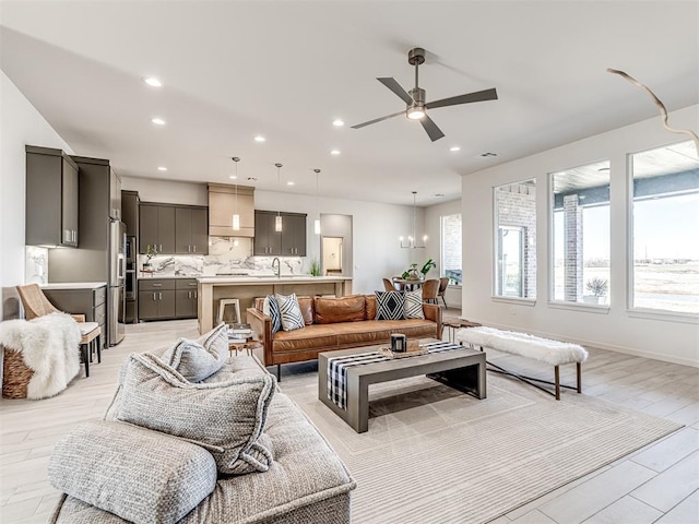 living room featuring light wood-type flooring, ceiling fan with notable chandelier, and recessed lighting
