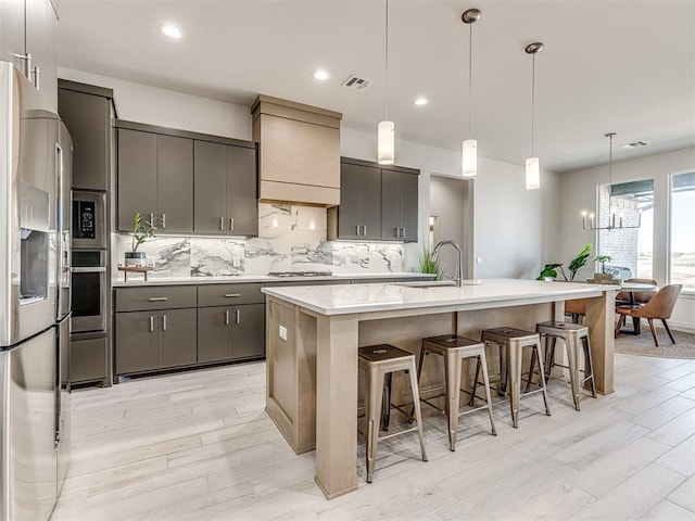 kitchen featuring tasteful backsplash, a breakfast bar, light wood-style flooring, light countertops, and appliances with stainless steel finishes