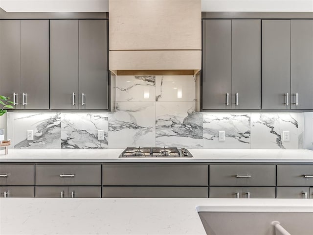 kitchen with tasteful backsplash, stainless steel gas stovetop, and gray cabinets