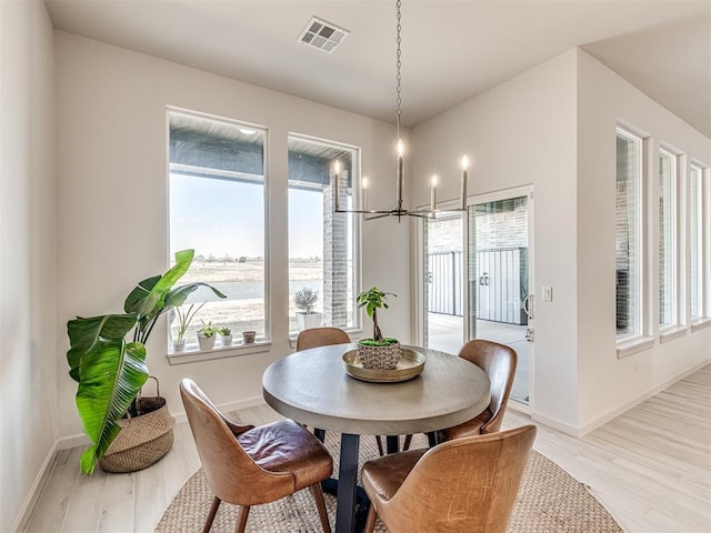 dining room featuring light wood-style floors, a notable chandelier, visible vents, and a healthy amount of sunlight