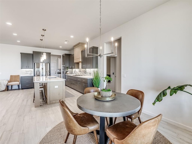 dining area featuring light wood-style flooring, an inviting chandelier, baseboards, and recessed lighting