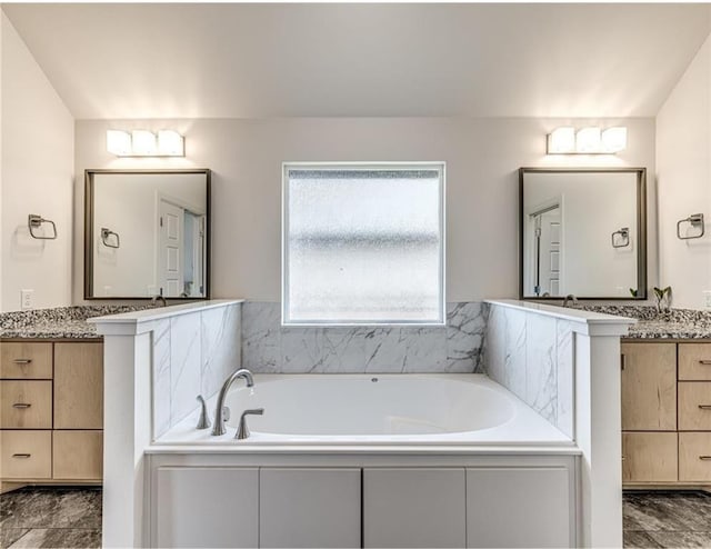 full bathroom featuring two vanities and a garden tub