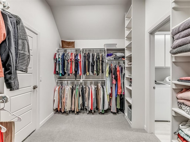 walk in closet with carpet floors, washer / dryer, and vaulted ceiling