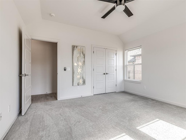 unfurnished bedroom with a closet, baseboards, carpet flooring, and vaulted ceiling