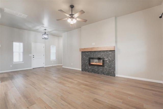 unfurnished living room featuring light wood-style flooring, a ceiling fan, and baseboards