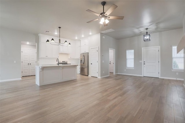 kitchen featuring open floor plan, baseboards, light countertops, and stainless steel fridge