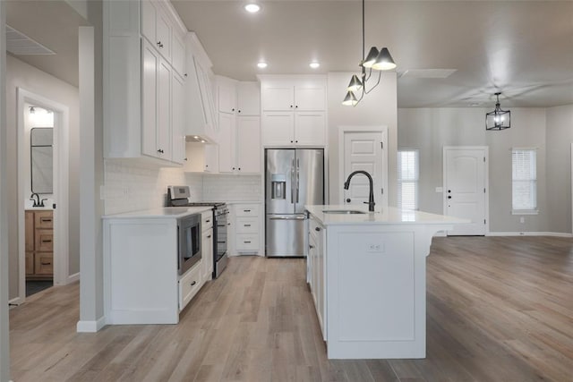 kitchen with white cabinets, appliances with stainless steel finishes, light countertops, a sink, and baseboards