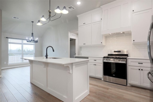 kitchen featuring a chandelier, stainless steel gas range, light countertops, a sink, and backsplash