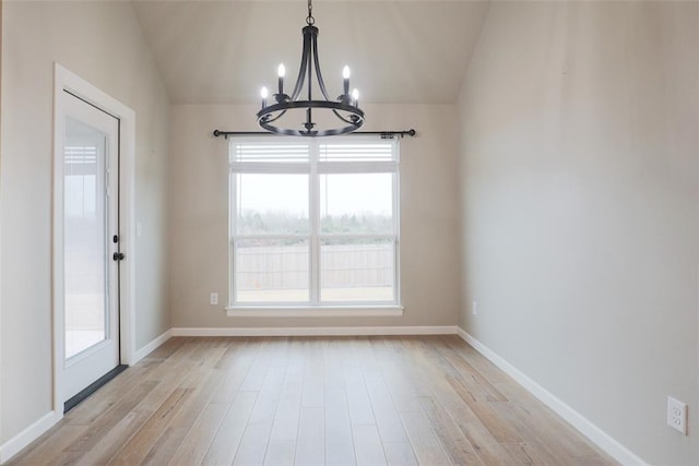 unfurnished dining area featuring baseboards, vaulted ceiling, a notable chandelier, and light wood-style floors
