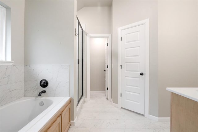 bathroom with a bath, a shower stall, marble finish floor, and baseboards