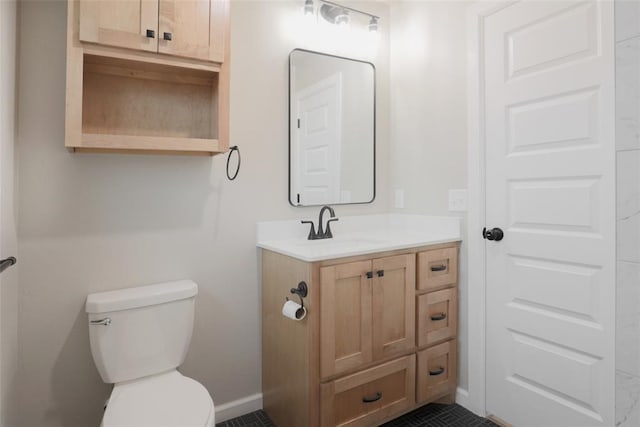 half bathroom featuring tile patterned flooring, vanity, baseboards, and toilet