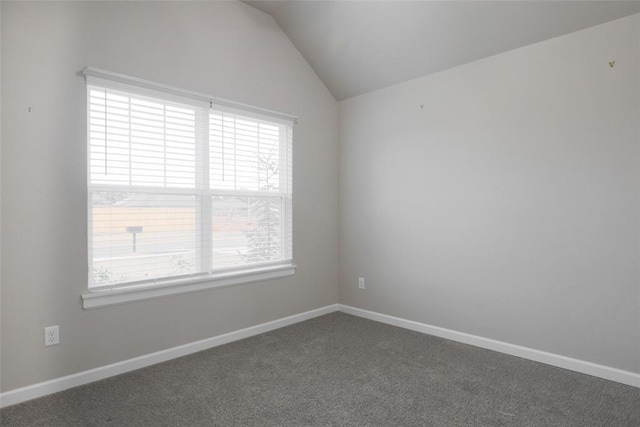 unfurnished room with baseboards, a healthy amount of sunlight, dark colored carpet, and lofted ceiling