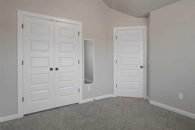 unfurnished bedroom featuring a closet, carpet flooring, baseboards, and vaulted ceiling