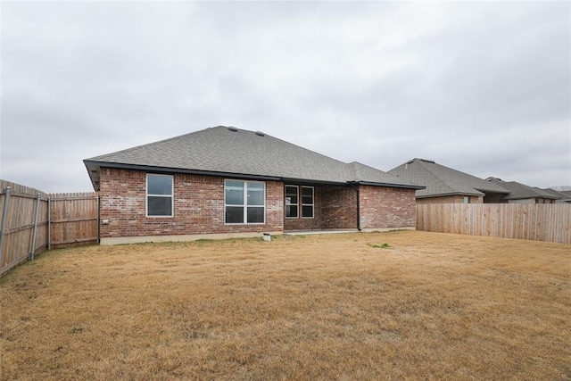 back of house featuring a yard, a fenced backyard, and brick siding