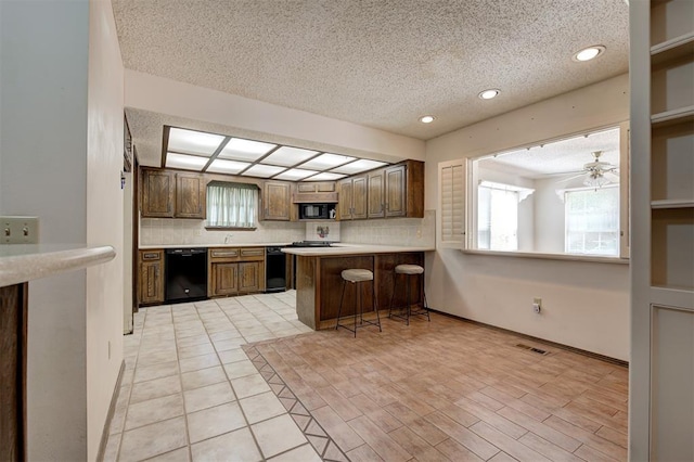 1113 Bank Side Cir, Edmond, OK 73012 - kitchen featuring black appliances, a wealth of natural light, decorative backsplash, and a textured ceiling