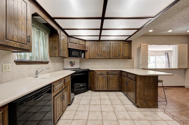 1113 Bank Side Cir, Edmond, OK 73012 - kitchen featuring a peninsula, a sink, tasteful backsplash, a kitchen bar, and black appliances
