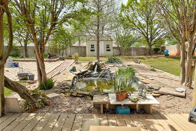 1113 Bank Side Cir, Edmond, OK 73012 - view of yard featuring a garden pond, a fenced backyard, an outbuilding, and a storage unit