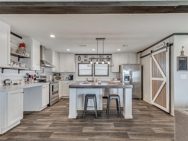 28737 Oakwood Meadows Dr, Cashion, OK 73016 - kitchen featuring wall chimney range hood, white cabinetry, a barn door, and stainless steel appliances
