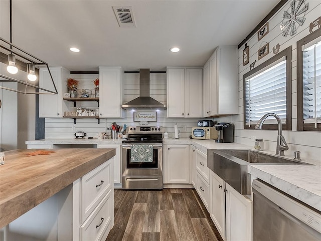 28737 Oakwood Meadows Dr, Cashion, OK 73016 - kitchen with visible vents, a sink, wall chimney range hood, stainless steel appliances, and butcher block countertops