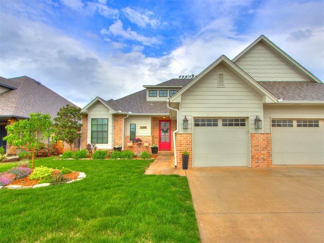 craftsman house featuring a shingled roof, brick siding, a garage, a front yard, and concrete driveway