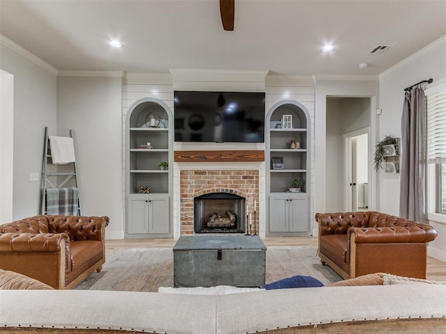 living room with crown molding, wood finished floors, visible vents, and a fireplace
