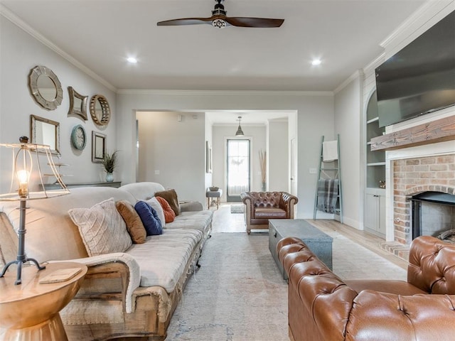 living room with built in features, ornamental molding, a ceiling fan, and a brick fireplace