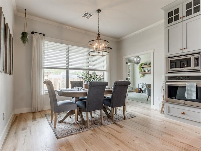 dining space with visible vents, crown molding, an inviting chandelier, baseboards, and light wood finished floors