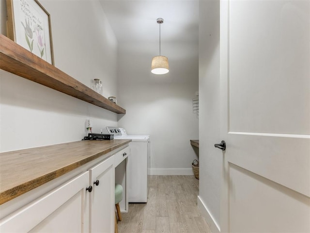 washroom featuring cabinet space, separate washer and dryer, baseboards, and light wood-style flooring