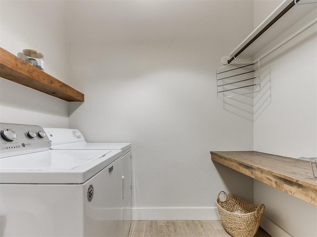 clothes washing area with independent washer and dryer, laundry area, baseboards, and light wood-type flooring