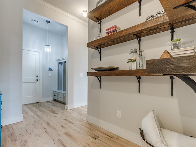 interior space with baseboards, ornamental molding, light wood finished floors, and visible vents